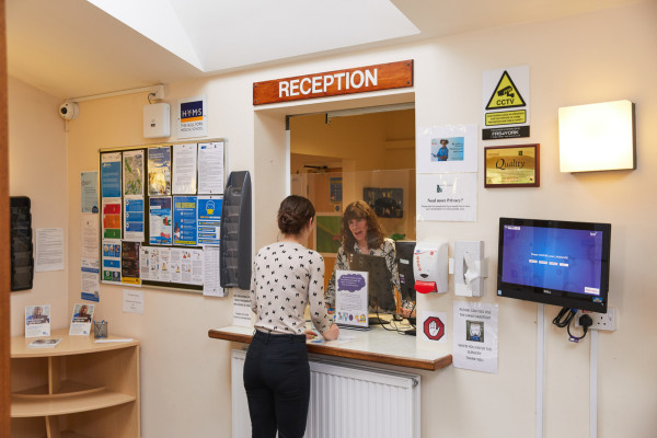A photo showing a patient speaking to a receptionist at park view surgery