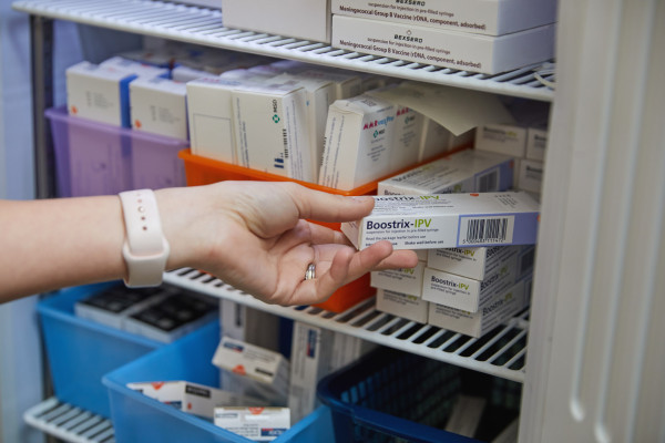 A photo showing a clinician getting a vaccine out of the fridge